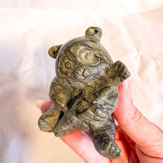 Hand holding a crystal panda sculpture of a bear against a soft background
