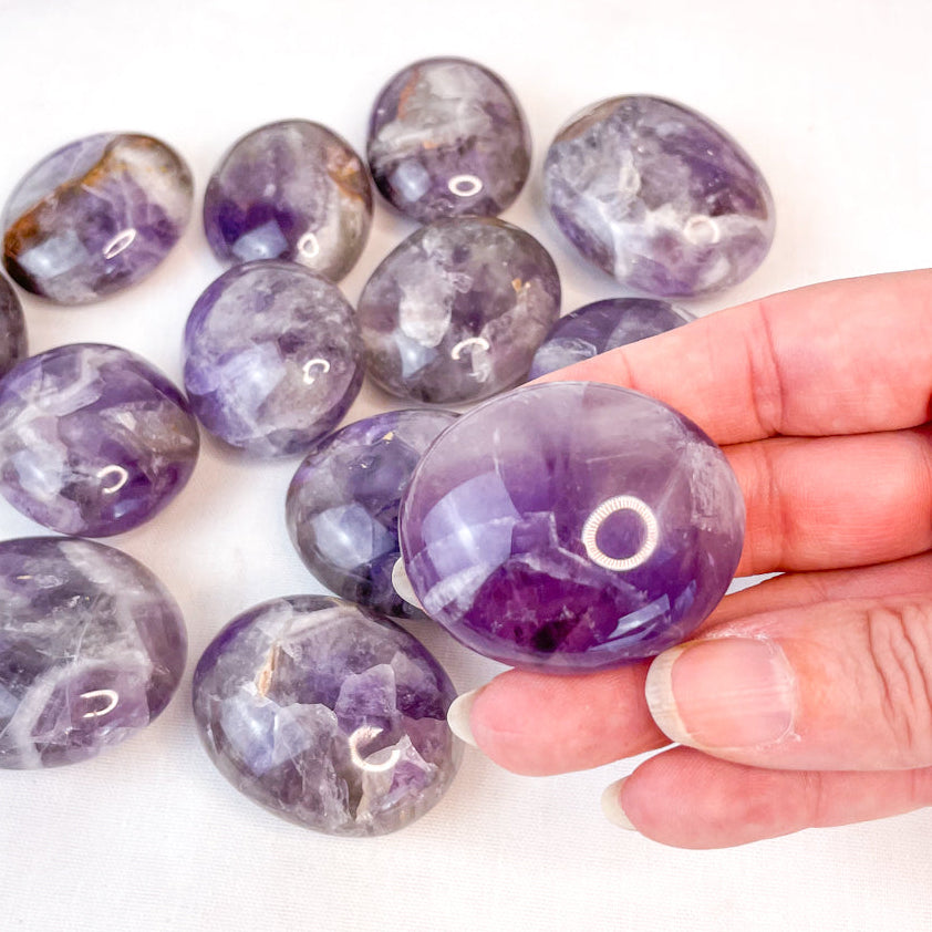 Amethyst stones with a hand holding one stone on a white background