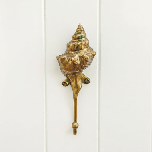 Gold shell-shaped hook on a white background
