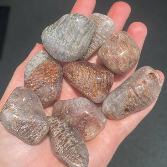 Hand holding a collection of polished stones with a dark background