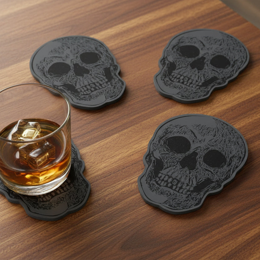 Four black skull-shaped coasters on a wooden surface