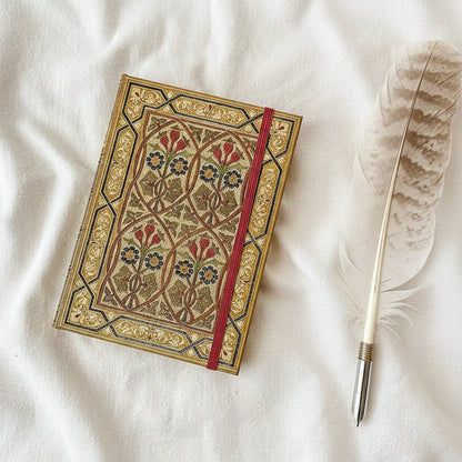 Decorative notebook with floral patterns and a red strap on a white fabric background