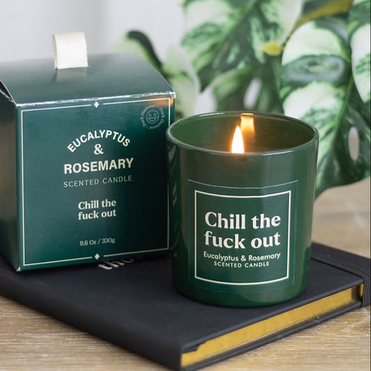 Green scented candle with 'Chill the fuck out' text next to its packaging on a wooden surface.