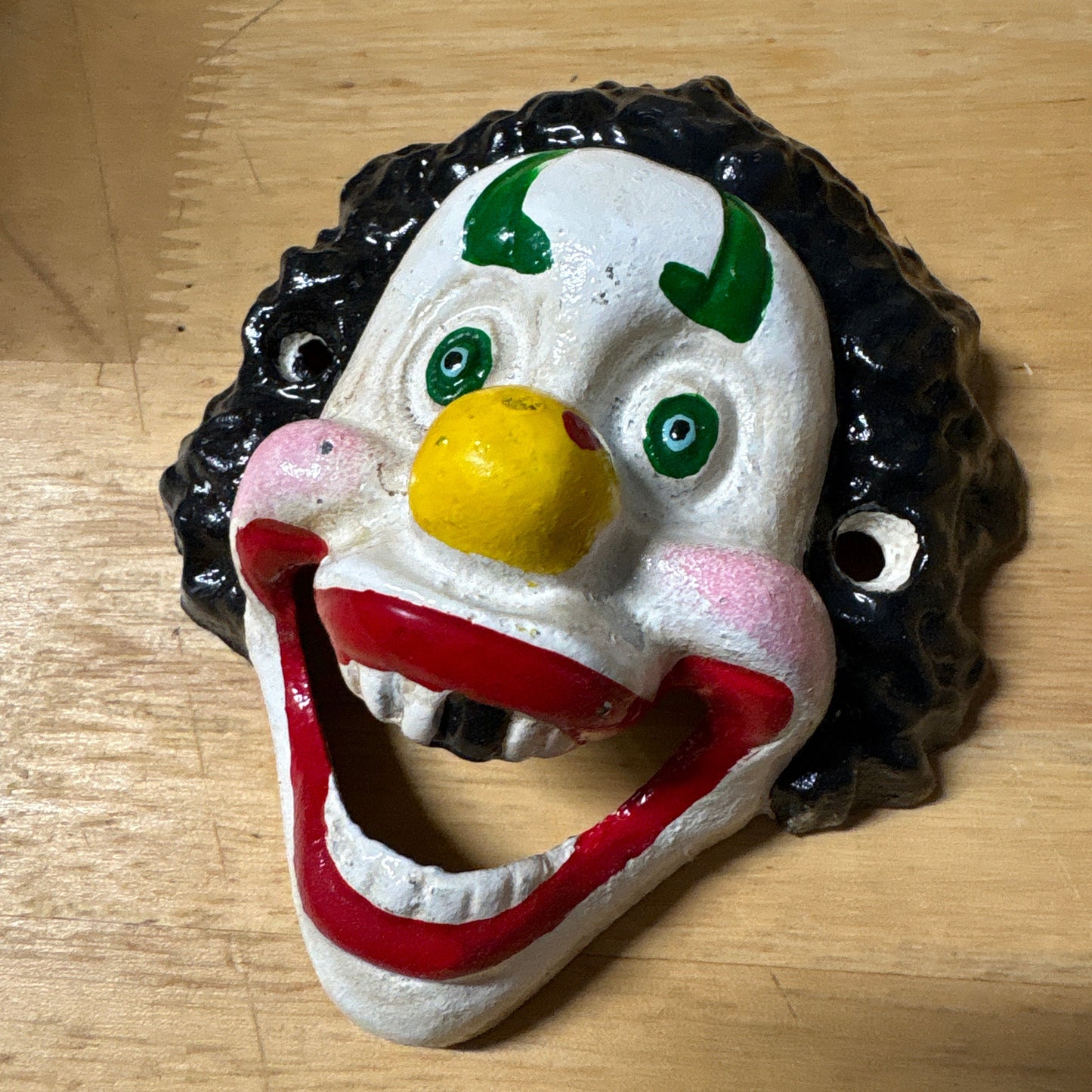 Colorful clown face bottle opener on a wooden surface