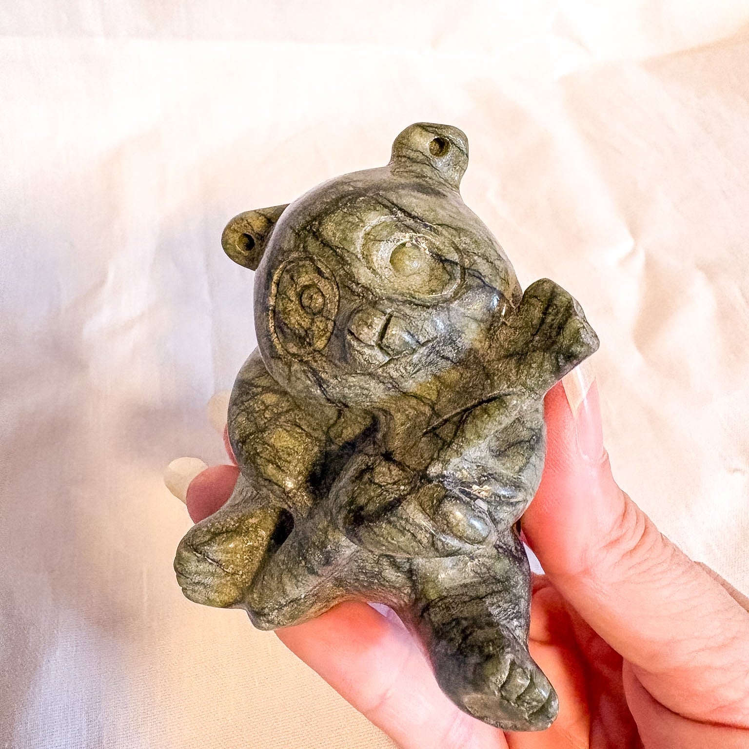 Hand holding a crystal panda sculpture of a bear against a soft background