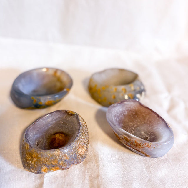 Four crystal bowls with polished in and stone finish out on a white fabric background