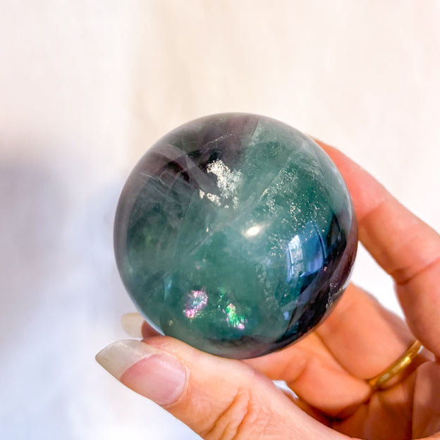 Fluorite crystal polished sphere with rainbow inclusions 330g
