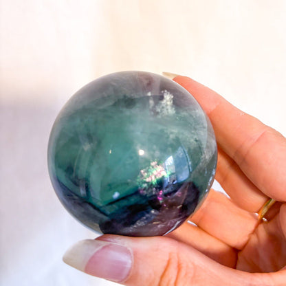 Fluorite crystal polished sphere with rainbow inclusions 330g