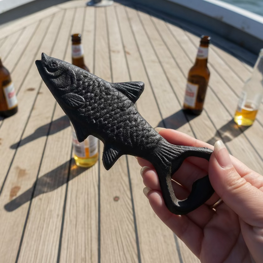 Hand holding a fish-shaped bottle opener on a wooden surface