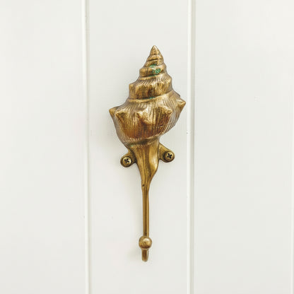 Gold shell-shaped hook on a white background